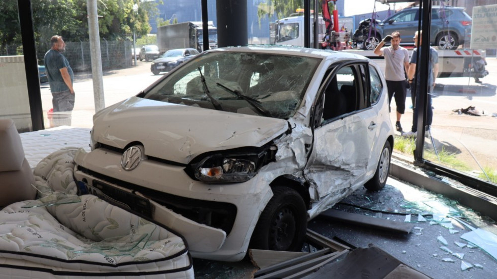 Der weiße Kleinwagen steht mitten im Schaufenster eines Möbelgeschäftes.