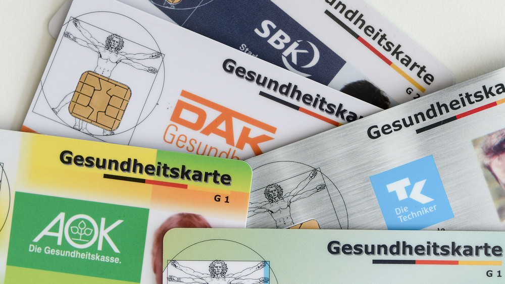 Gesundheitskarten verschiedener Krankenkassen liegen auf einem Tisch.
