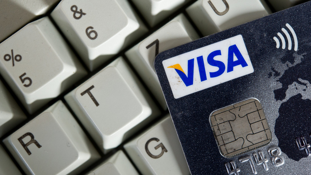 Eine Visa-Karte liegt auf einer Computertastatur.
