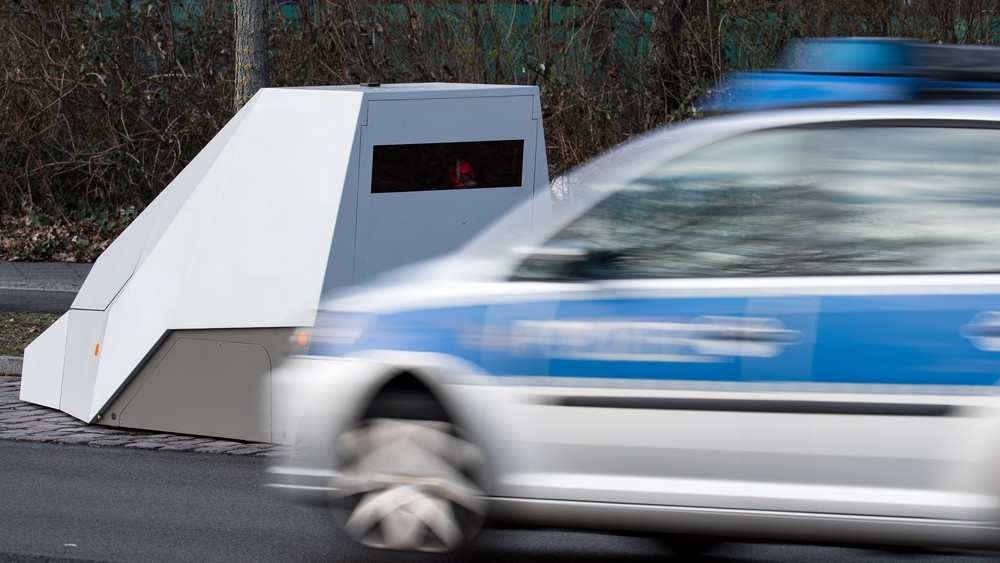 Ein Polizeiauto fährt an einem mobilen Blitzwagen vorbei