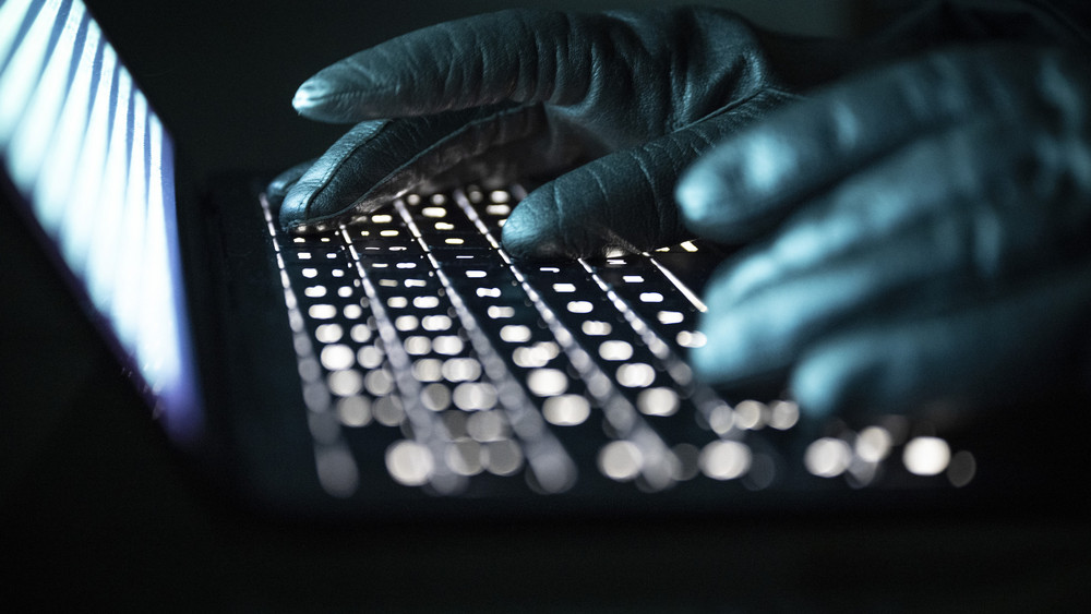 Hände mit Handschuhen tippen auf Laptop