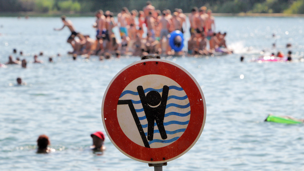 Ein Schild warnt im Badesee in Bensheim Schwimmerinnen und Schwimmer vor einem stark abfallenden Ufer.