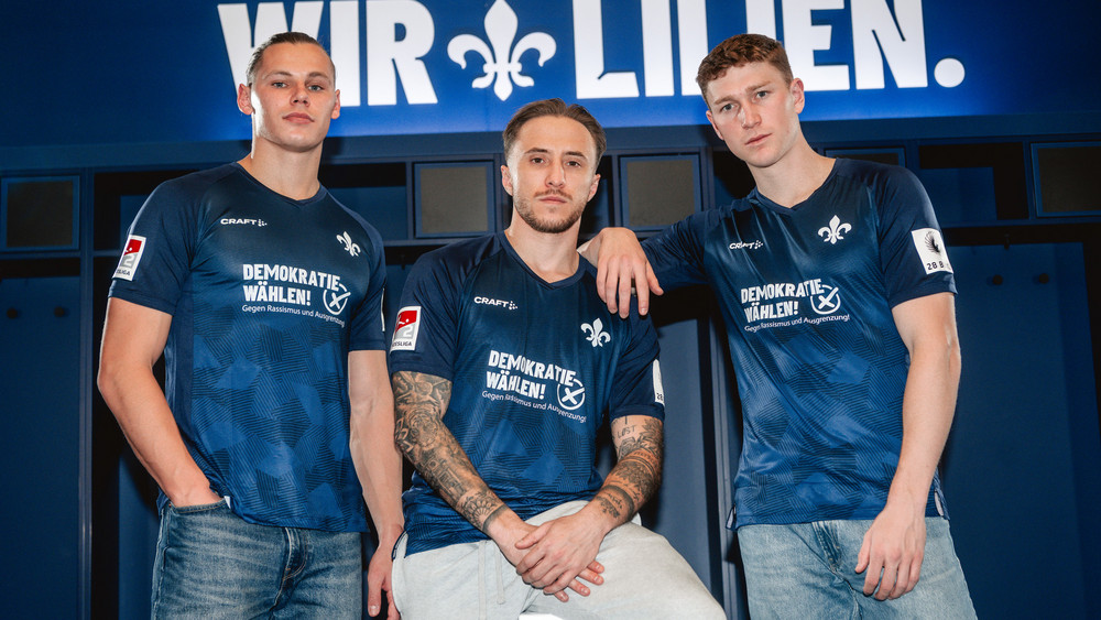 Die Lilien-Spieler Lakenmacher, Marseiller und Kapitän Riedel (von links nach rechts) mit dem Sondertrikot für das Spiel am Sonntag.