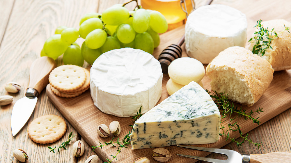 Käse und Weintrauben liegen auf einem Holzbrett