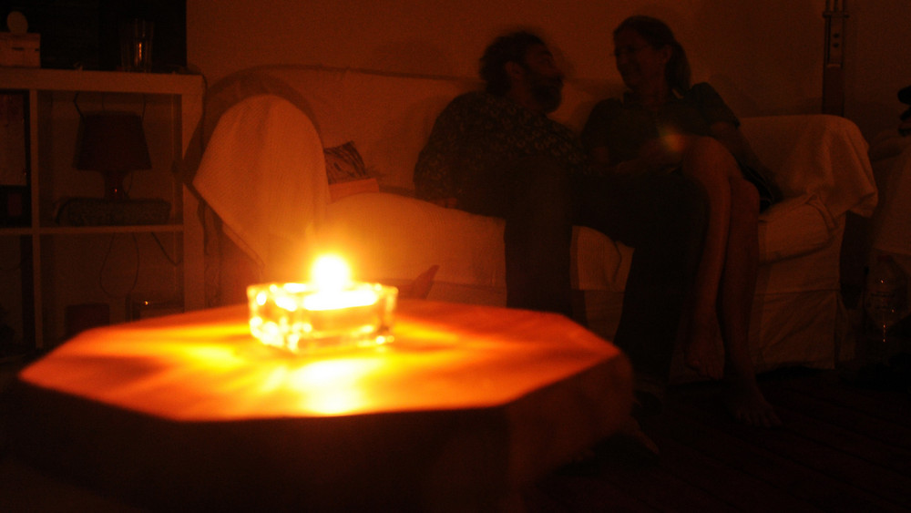 Ein Paar sitzt während eines Stromausfalls bei Kerzenschein in einer Wohnung