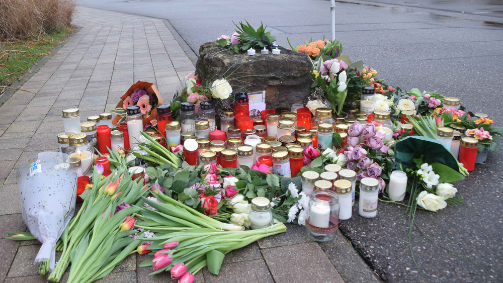 Blumen und Kerzen zum Gedenken an das Opfer liegen vor einer Schule.