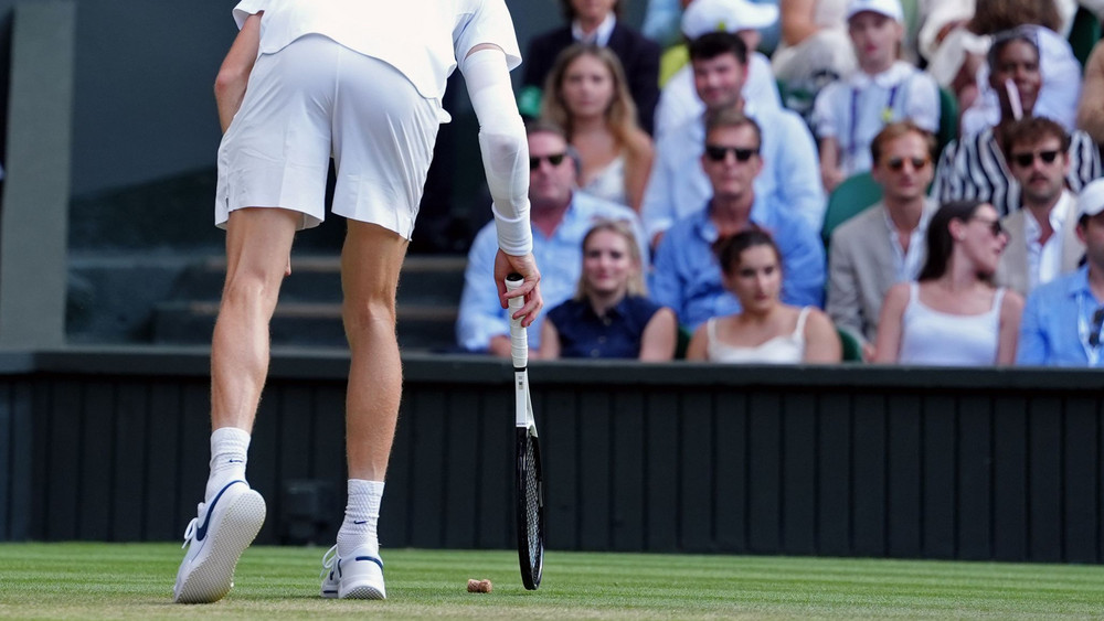 Kuriose Szene: Jannik Sinner fischt einen Champagnerkorken vom Rasen.
