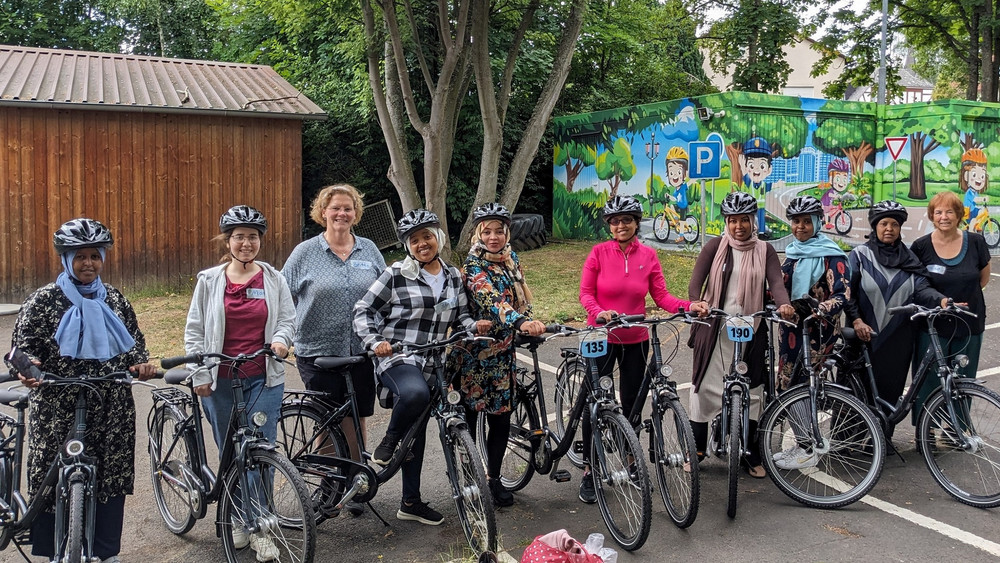 Acht Frauen auf Fahrrädern sind bereit für ihren Fahrradfahrkurs.