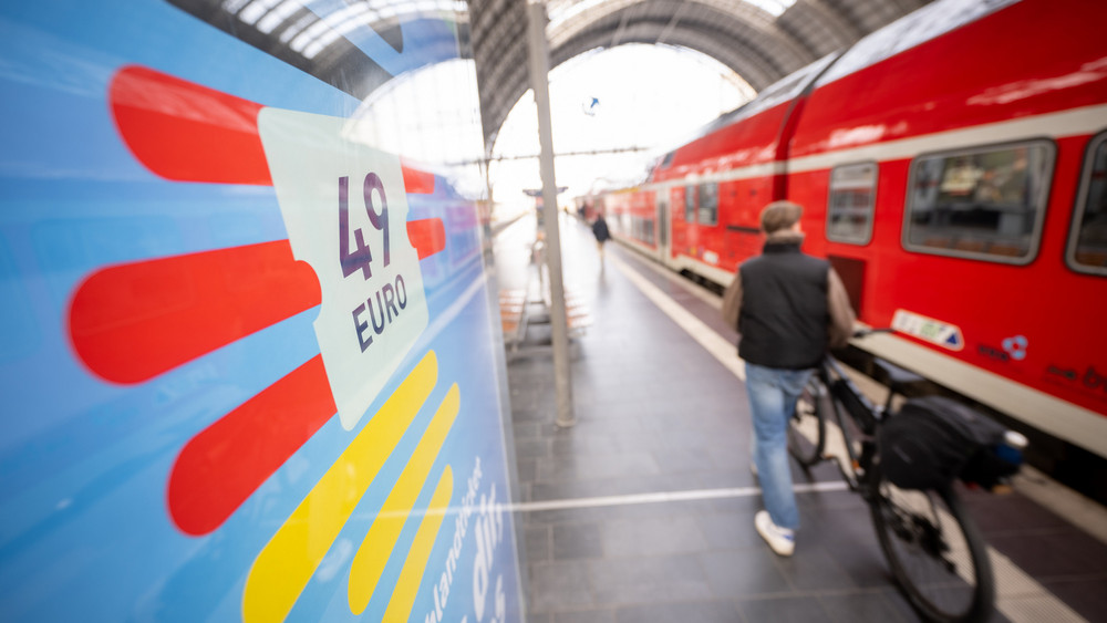 Auf einem Bahnhof steht eine Werbetafel zum Deutschlandticket. 