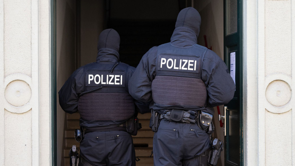 Zwei vermummte Polizeibeamte stehen in einem Hauseingang
