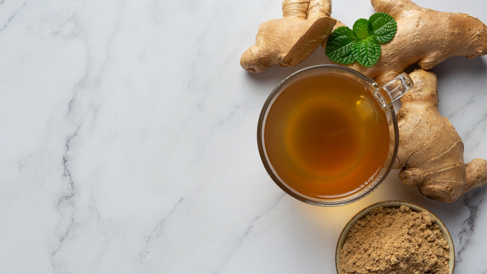 Ein Ingwertee und eine Ingwerknolle vor Mamorhintergrund