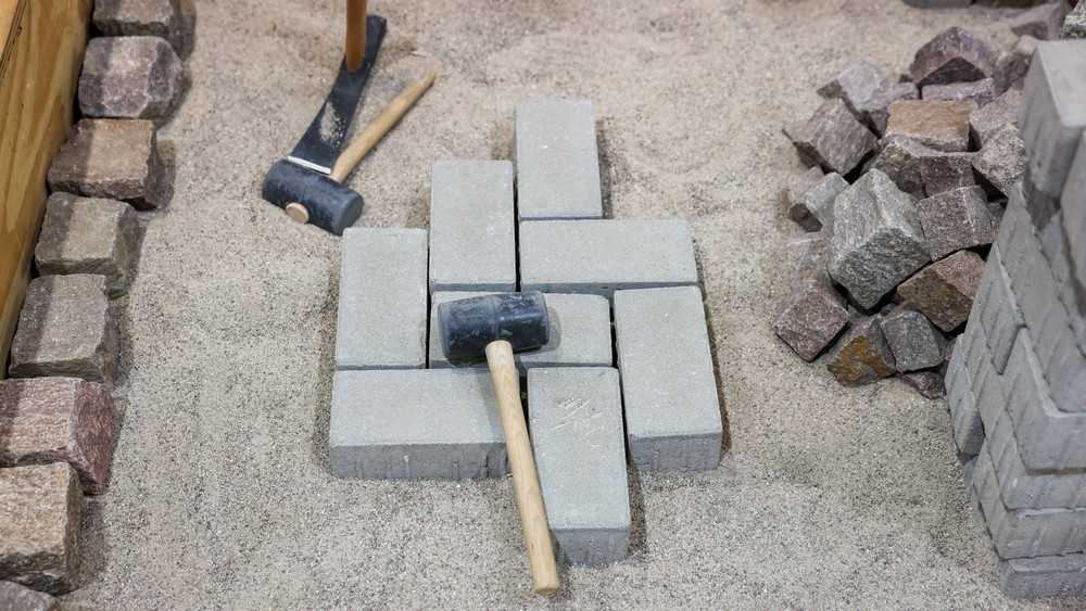 Übungsfeld der Handwerkerschaft im Straßenbau. Auf Pflastersteinen liegt ein Hammer.