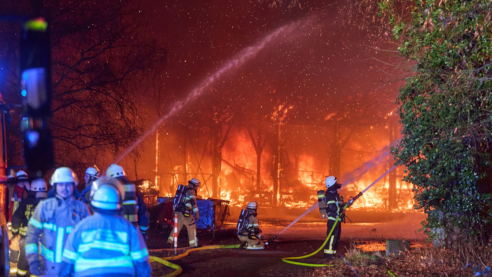 Einsatzkräfte der Feuerwehr bekämpfen in der Silvesternacht den Großbrand einer Lagerhalle.