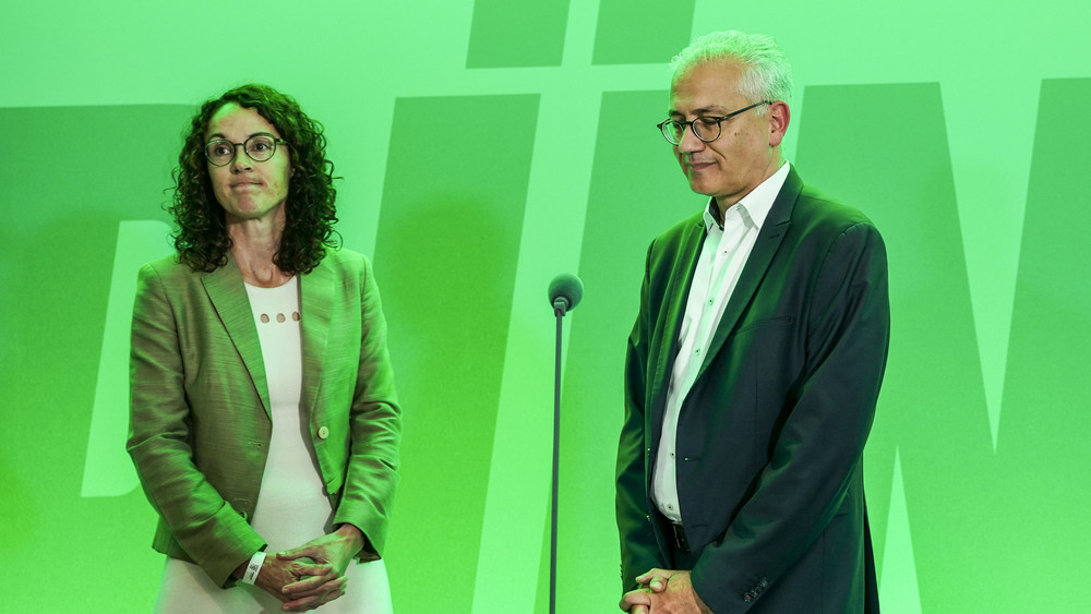 Angela Dorn, Wissenschaftsministerin in Hessen, und Tarek Al-Wazir, stellvertretender Ministerpräsident und Wirtschaftsminister von Hessen, stehen am Wahlabend im Oktober in grünes Licht getaucht vor ihren Parteifreunden.