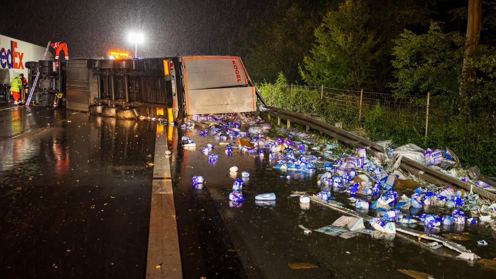 Ein umgestürzter Lastwagen liegt nach einem Unfall auf der A3 bei Niedernhausen. Die Ladung, Waschmittelpackungen, liegen verstreut über die Fahrbahn.