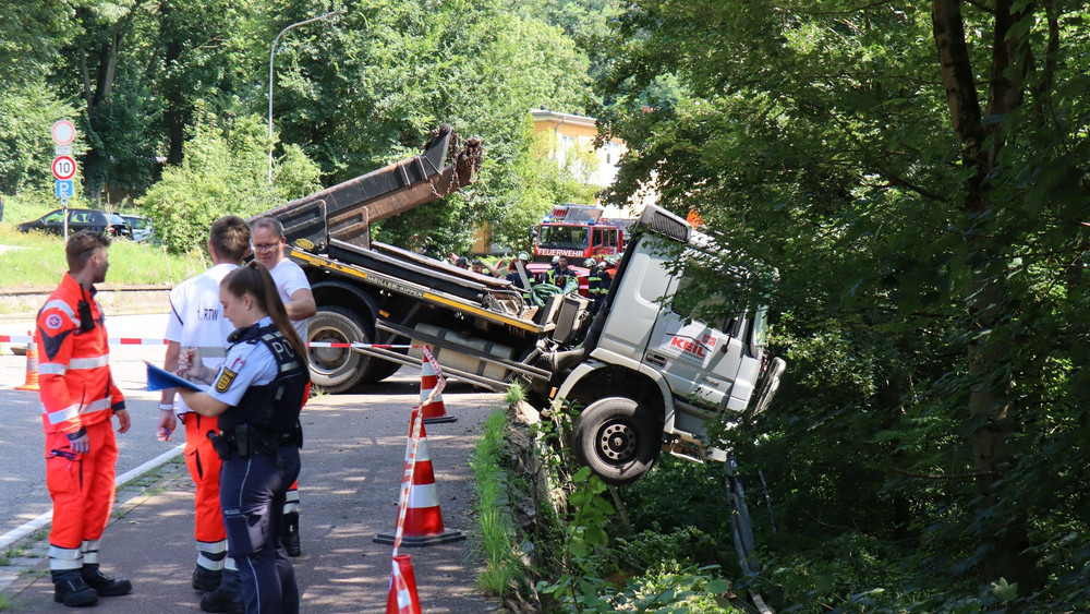 Der LKW hängt über der Böschung.