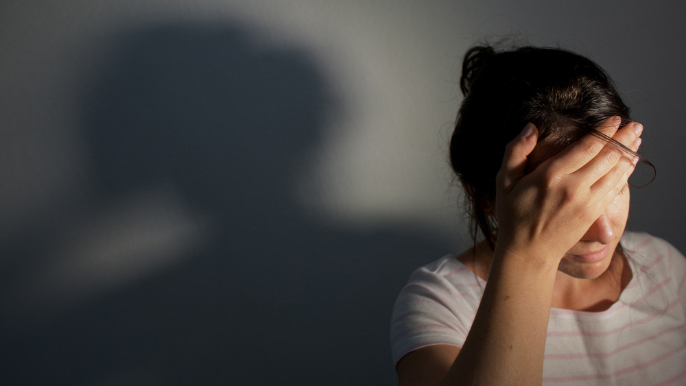 Frau fasst sich mit Hand an die Stirn