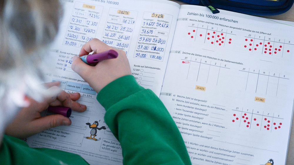 In einer Grundschule arbeitet ein Schüler einer vierten Klasse in einem Heft an seinen Mathematikaufgaben.