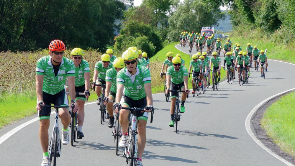 Die Radfahrer in grünen Trikots mit gelben Fahrradhelmen.