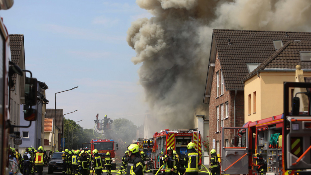 Rauch und Flammen schlagen aus einem Gebäude. Ein Motorradladen ist in Sankt Augustin im Rhein-Sieg-Kreis in Brand geraten. Bei den Löscharbeiten kamen eine Frau und ein Mann der Freiwilligen Feuerwehr ums Leben.