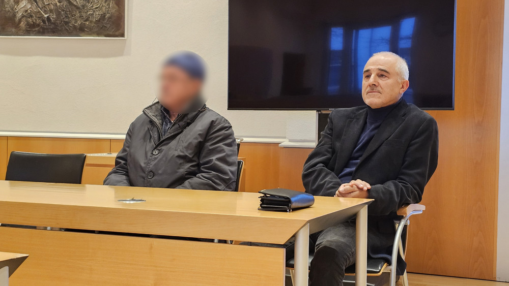 Der Angeklagte sitzt neben seinem Dolmetscher auf der Anklagebank.