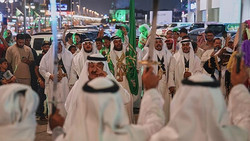 Menschen feiern saudischen Nationalfeiertag mit Fahnen und Militärparade