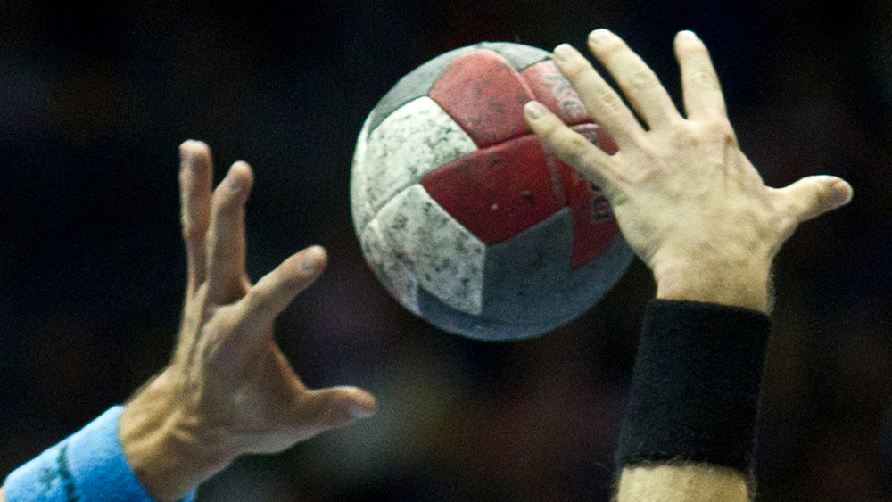 Zwei Hände kämpfen um einen Handball