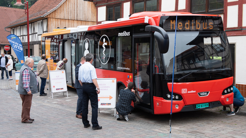 Medibus hält vor einem Haus, Patienten stehen davor