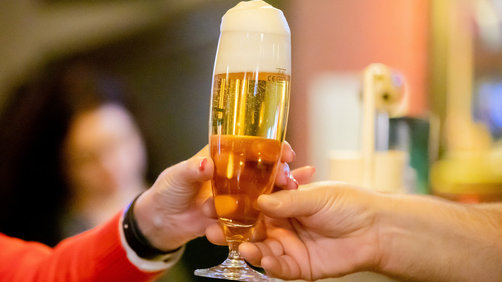 Ein volles Glas Bier wird weitergereicht.
