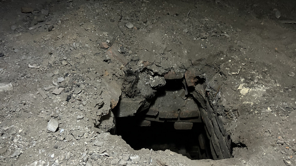 Durch ein Loch im Boden ist ein Gewölbe zu sehen.