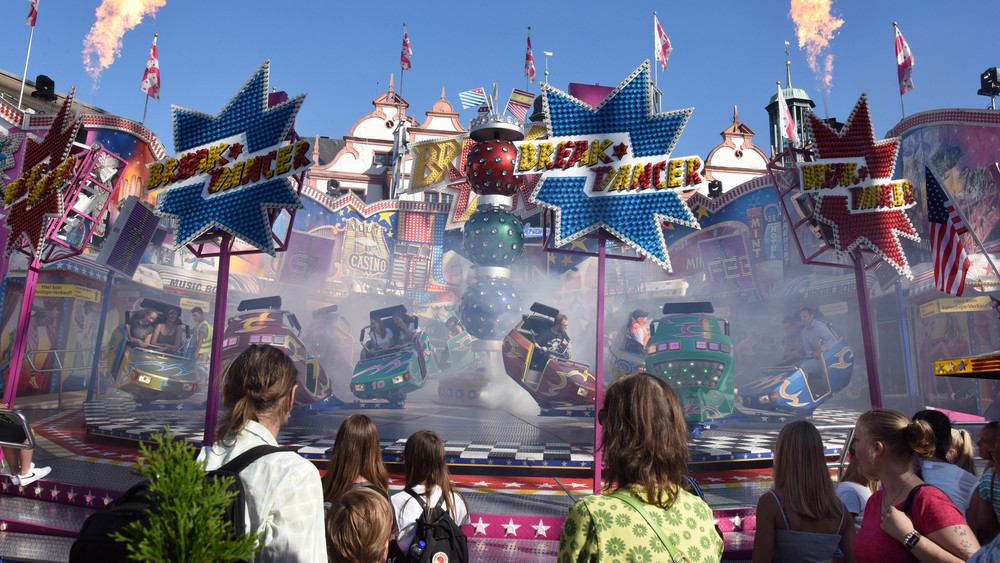 Am Eröffnungstag des Darmstädter Heinerfest, das größte Volksfest Südhessens, stehen Besucher am Fahrgeschäft "Break Dancer" und schauen zu.