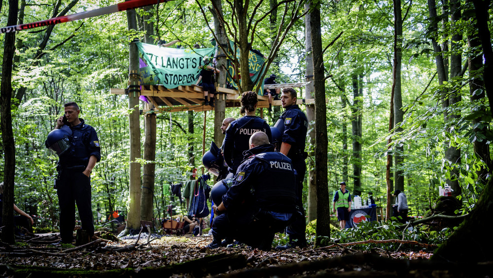 Blick ins Protestcamp bei Langen mit Baum-Plattform und Polizei vor Ort