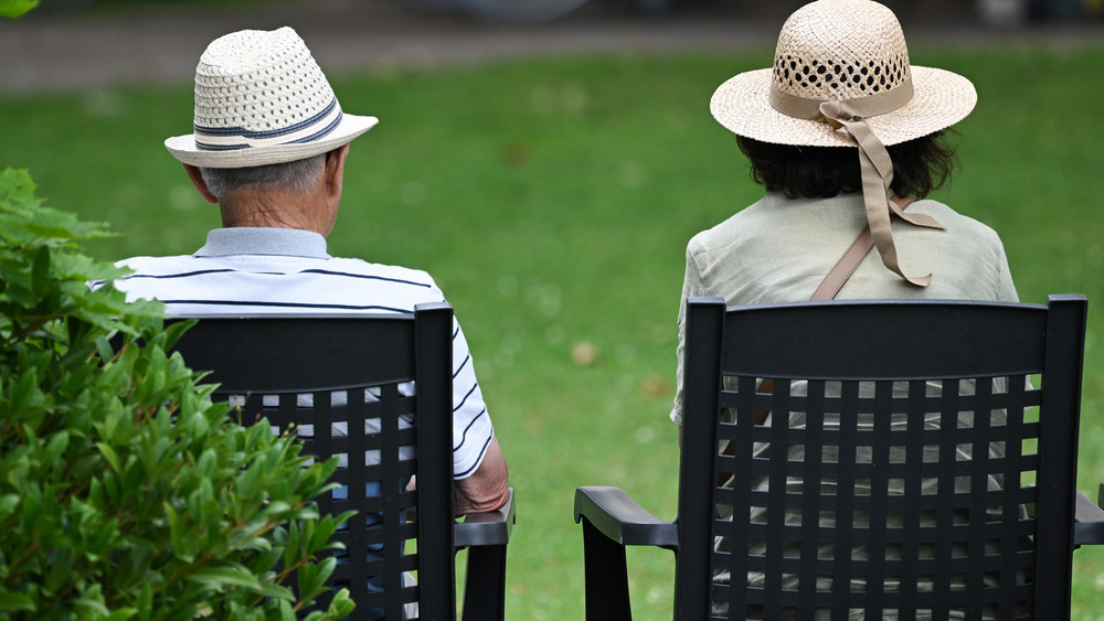 Zwei Boomer mit Hut sitzen im Park