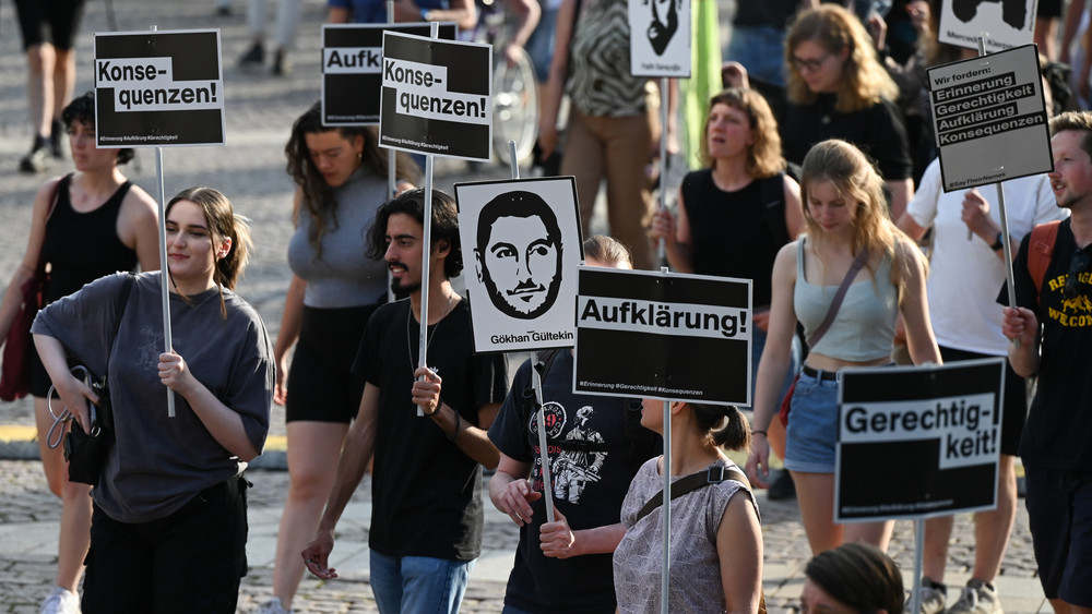 Teilnehmer eines Demonstrationszuges halten nach einer Kundgebung für die Opfer des Anschlags von Hanau Plakate mit der Aufschrift "Aufklärung", "Konsequenzen" und "Aufklärung" hoch.