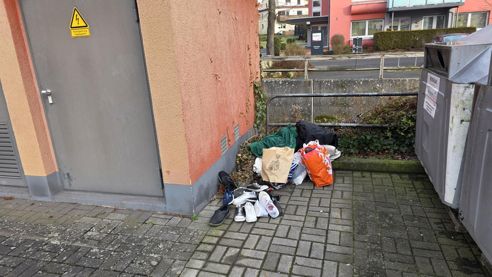 Rechts die Altglascontainer. Links standen bis 2025 Altkleidercontainer. Obwohl die abgebaut wurden, legen dort immer noch Menschen ihre nicht mehr benötigten Kleider und Schuhe ab. 