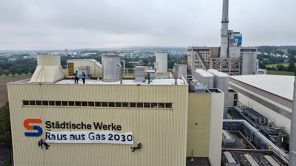 Am Gaskraftwerk in Kassel  hängen zwei Aktivisten und ein Banner.