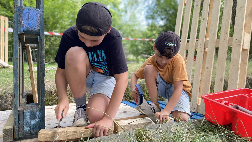 Der 12-Jährige Janosch (links) und sein Bruder Béla (7) beginnen gerade in der Woog eine Bar aufzubauen. In den Sommerferien findet dort das Angebot des Spielmobils statt. Kinder zwischen 4 und 15 dürfen dann dort ganz frei etwas aus Holz bauen. 