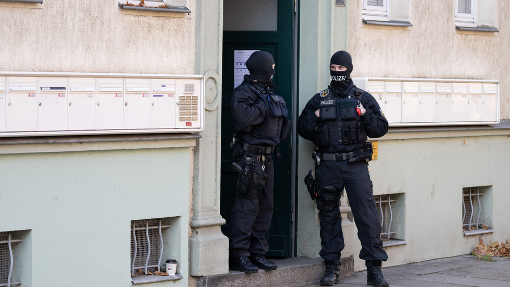 Polizisten stehen während einer Razzia gegen mutmaßliche Rechtsextreme in einem Hauseingang im Dresdner Stadtteil Cotta.