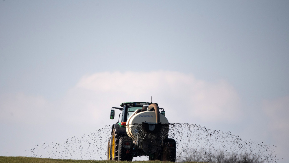 Ein Landwirt düngt mit seinem Traktor eine Wiese.