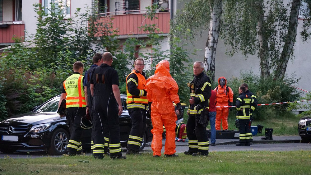 Zu sehen sind mehreren Feuerwehrmänner, davon zwei in orangenen Gefahrgutanzügen.