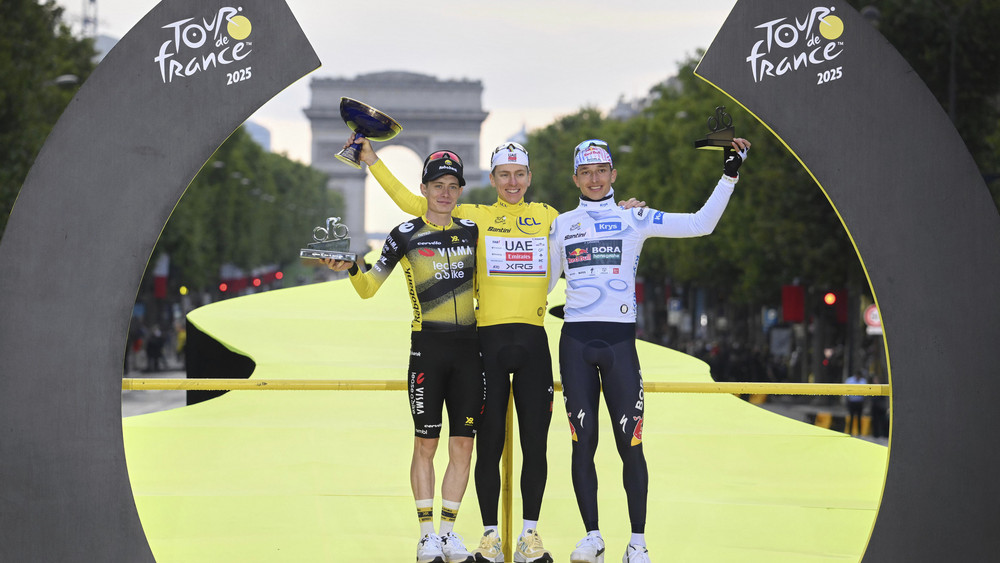  Der slowenische Tour de France-Sieger Tadej Pogacar (M), der zweitplatzierte Däne Jonas Vingegaard (l) und der Deutsche Florian Lipowitz (r) feiern auf dem Podium nach der letzten Etappe.