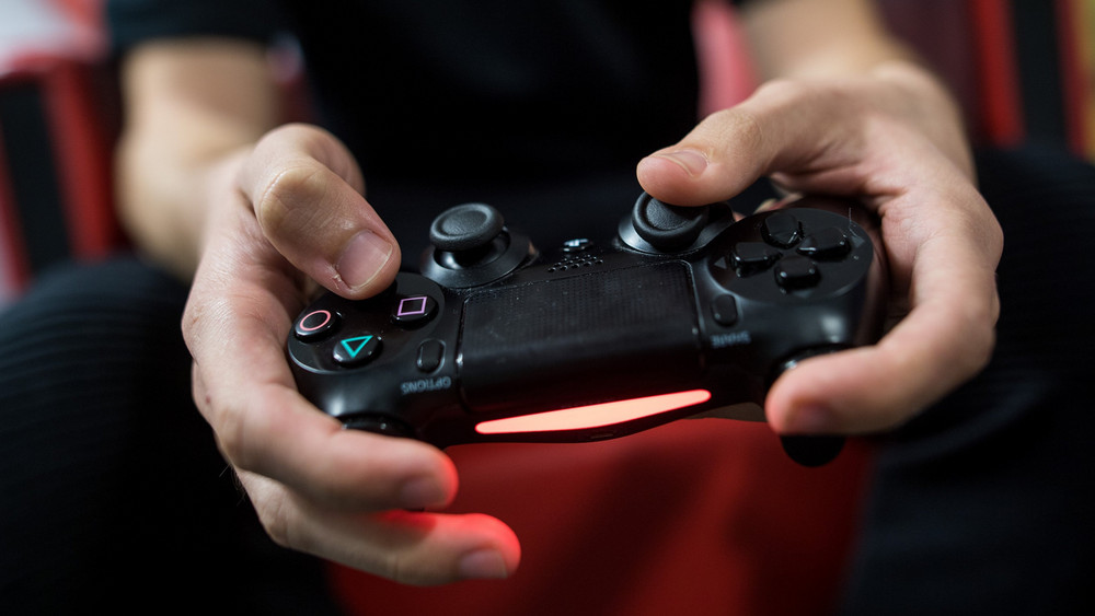 Eine Person hat einen Spielekonsolen-Controller in der Hand