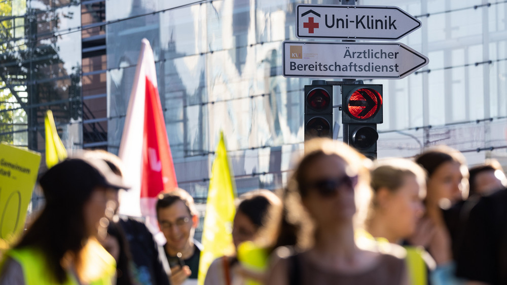 Streikende ziehen in Frankfurt an einem Straßenschild "Uni-Klinik" vorbei. Die Gewerkschaft Verdi hat die Beschäftigten am  Mittwoch zu einem Warnstreik aufgerufen.