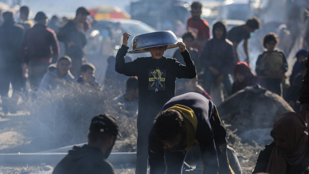Menschen versammeln sich in einem Lager für vertriebene Palästinenser an Lehmöfen, um hier Essen zuzubereiten und Brot zu backen. 