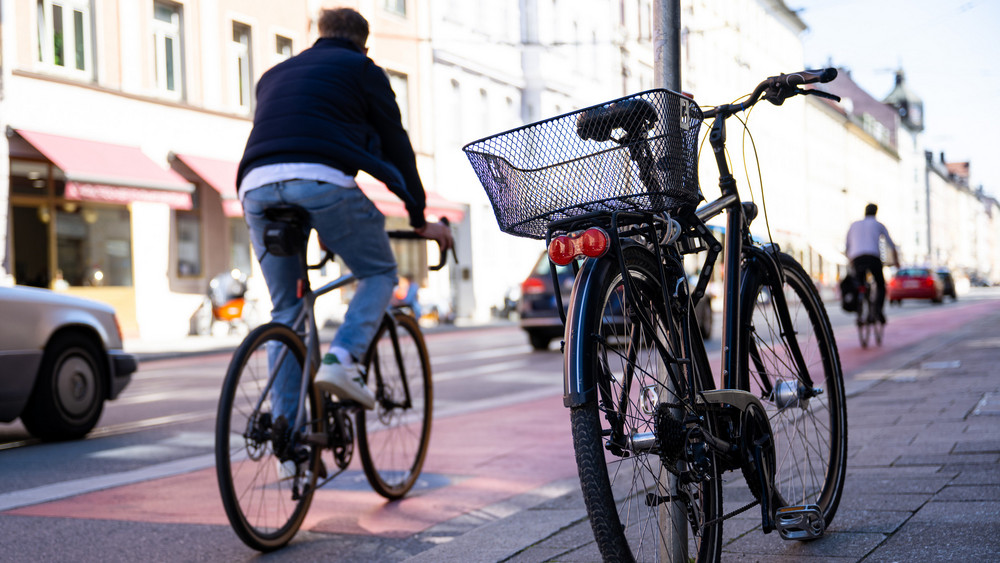 Für das Klima in die Pedale treten: Beim "Stadtradeln“ geht es darum, welche Kommune die fahrradaktivste ist (Symbolbild). Auf dem Foto ist ein Fahrradfahrer in der Stadt zu sehen, der auf einem roten Fahrradstreifen fährt.