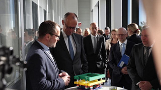 Merz tauscht sich mit Mikrochip-Forschern aus - AfD protestiert gegen Kanzler