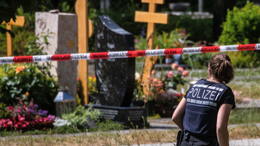 Eine Polizistin geht über den abgesperrten Teil an einem Tatort auf einem Friedhof. Durch den Wurf eines explodierenden Gegenstands auf eine Trauergemeinde gab es mehrere Verletzte.