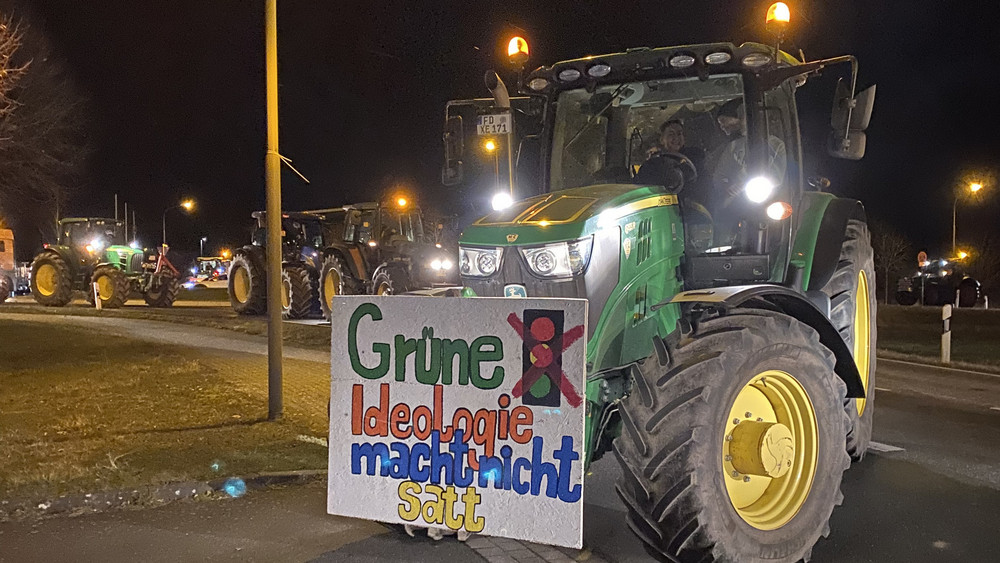 Ein Traktor mit Protest-Banner an der Front. Darauf steht "Grüne Ideologie macht nicht satt"