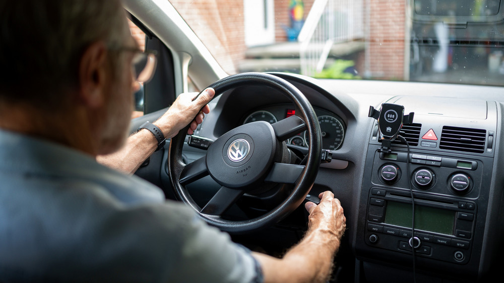 Ein älterer Mann steckt den Schlüssel in das Zündschloss eines Autos