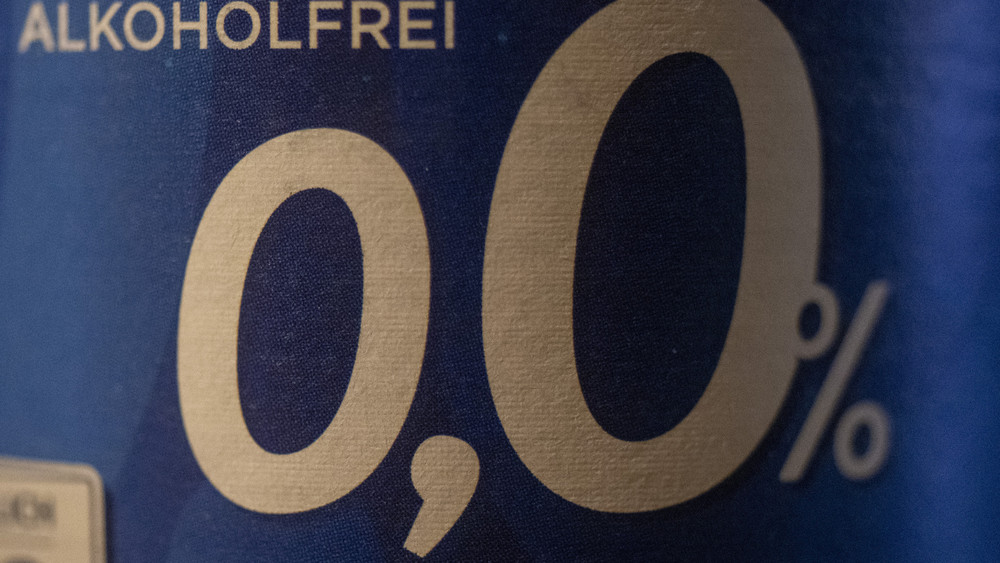 In einer Bar steht eine Flasche alkoholfreies Bier mit der Aufschrift „Alkoholfrei 0,0%“. Während der Fußball-EM erwarten Brauereien in Deutschland einen Anstieg beim Absatz von alkoholfreiem Bier (Symbolbild).